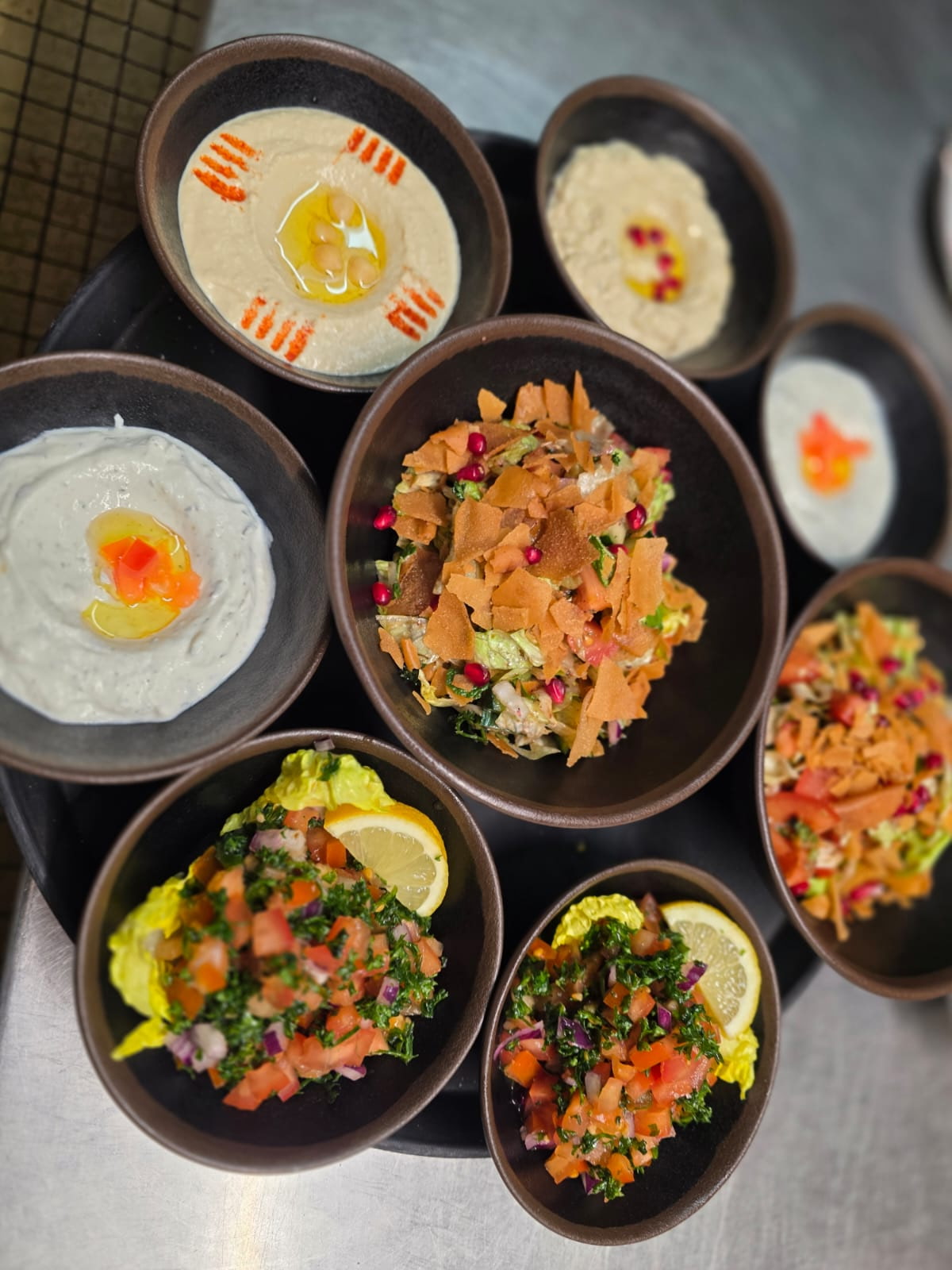 Assortiment de mezze servi en plusieurs bols : houmous, moutabal, fattouche, taboulé